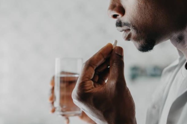 Figure 2 – A man following his medication getting ready to swallow a pill (Man Medicating Himself At Home Medicine Stock Photo - Download Image Now - Pill, Men, Capsule - Medicine - iStock).